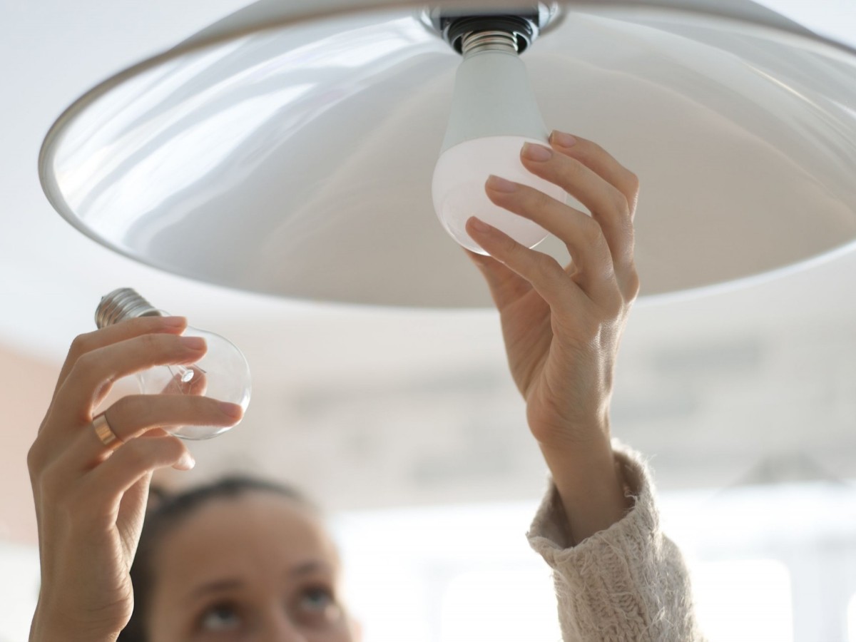 Kobieta dokonująca wymiany żarówki żarowej z gwintem E27 na LED