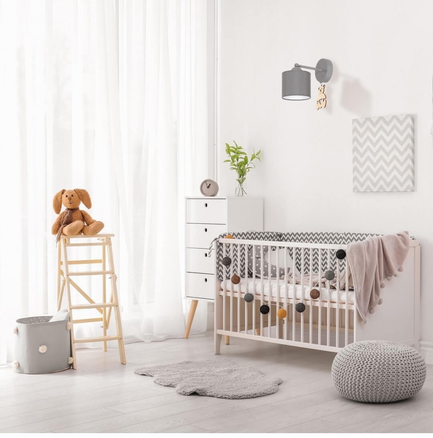 Szary kinkiet zawieszony nad dziecięcym łóżeczkiem