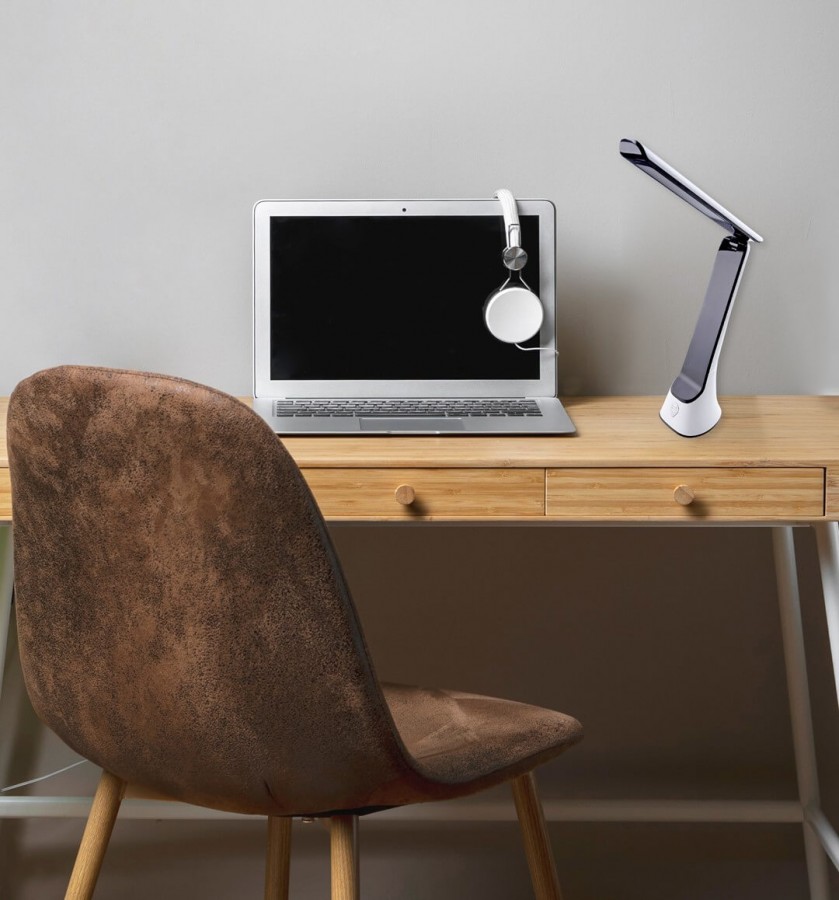 Nowoczesna lampka biurkowa na drewnianym biurku koło laptopa