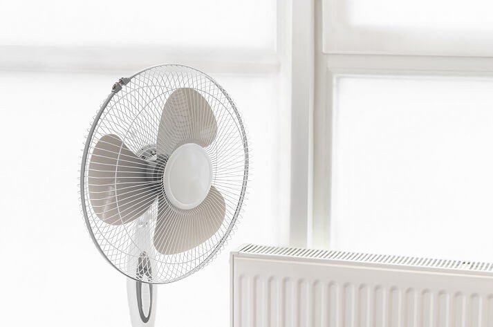 Wentylator stojący obok klimatyzatora w salonie 